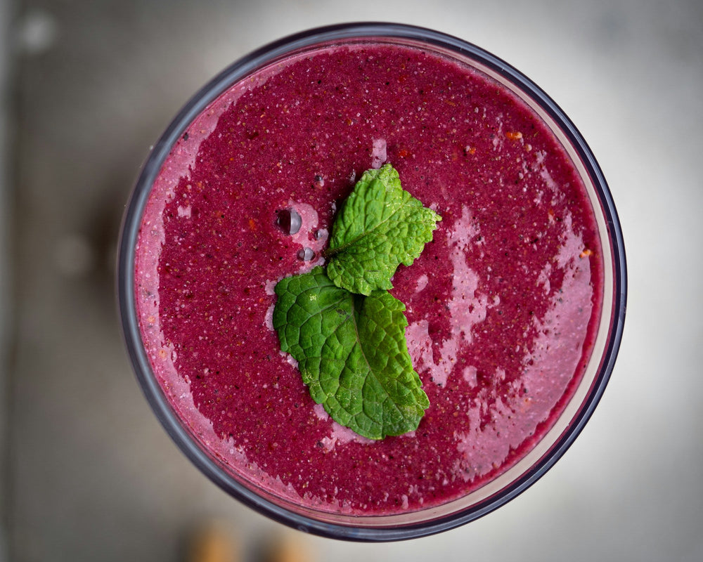Berry smoothie topped with fresh mint leaves, viewed from above